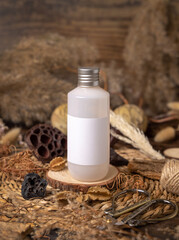 Cosmetic bottle with blank label on wood near natural decorations close up. Packaging Mockup