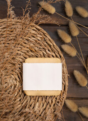 Soap bar with blank label on wattled placemat near Hare's Tail grass. Cosmetic Mockup