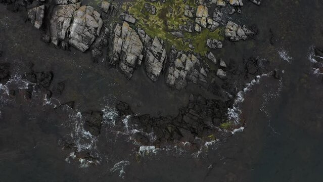 Birdseye view of waves hitting the shoreline in Bornholm, Danish island. Top down of the Ocean with drone.