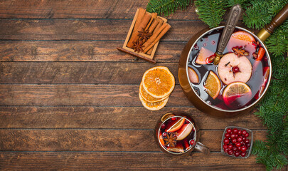 Obraz na płótnie Canvas Christmas mulled wine with fruit cranberries and spices on wooden background with copy space.
