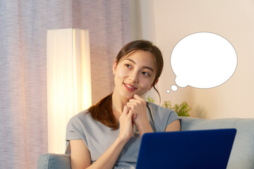 夜のリビングでノートパソコンを使いながら想像する女性　吹き出しあり