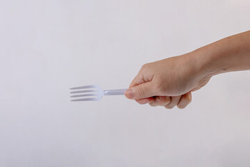 Hand and white fork plastic isolated on white close up