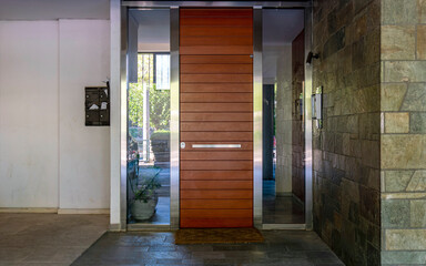 Modern residential building entrance stainless steel and wood door, Athens, Greece.