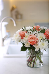 Vase with beautiful flowers on countertop in kitchen. Interior design
