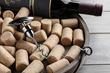 Tray with corkscrew, wine bottle and stoppers on wooden table, closeup