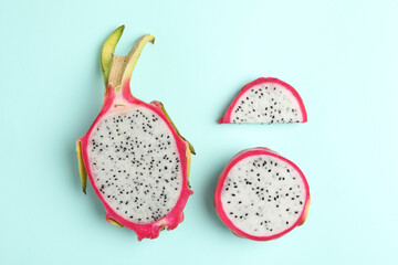 Delicious cut dragon fruit (pitahaya) on light blue background, flat lay