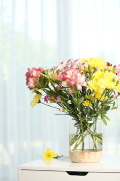 Vase with beautiful flowers on table near window indoors. Stylish element of interior design