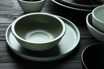 Stylish empty dishware on black wooden table