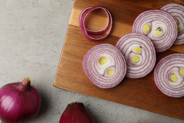 Red onion and wooden board on light grey table, flat lay