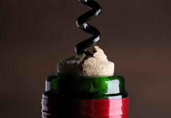 Opening wine bottle with corkscrew on dark background, closeup