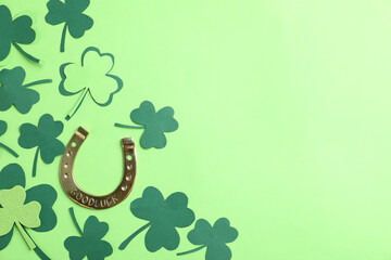 Flat lay composition with clover leaves and horseshoe on green background, space for text. St....