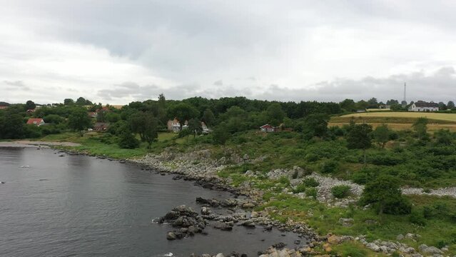 View over small red cabin at the coastline of the danish island Bornholm. Drone footage in Denmark in summer