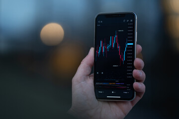 Trader looking at mobile phone with stock chart on screen