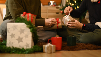 Cropped shot of two man celebrating Christmas, New Year at home together and exchange presents