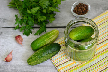 pickled cucumbers in jar on kitchen table with garlic and parsley
