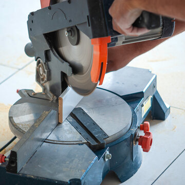Worker cutting baseboard on the circular saw before installing