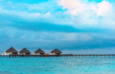 view from sea to island and water villas at day time with blue sky and beautiful clouds in the Maldives, the concept of luxury travel