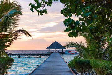 pier leading to the island at sunrise in the Maldives, the concept of luxury travel