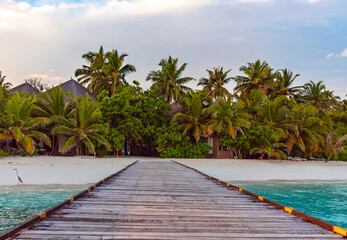 pier leading to the island at sunrise in the Maldives, the concept of luxury travel
