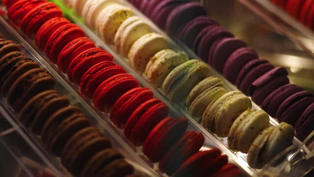 Slowmo pan left, past corner of glass case displaying decadent Paris macarons