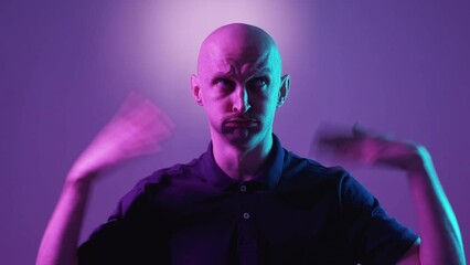 Heat system problem. Suffering man. Hot weather. Grimacing funny guy blowing himself with hands on purple blue neon light background.