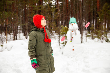 Fototapeta na wymiar Pre-teen girl in winter to sculpt a snowman