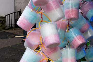 Sweet soft sugary cotton wool dessert in non-ecological polyethylene buckets on summer or autumn market stand. Sugar wall attracting children.