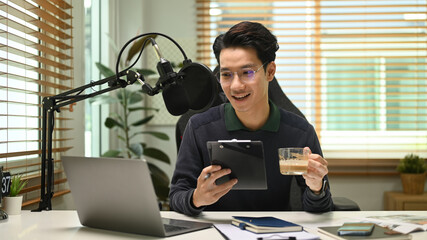 Man using microphone and recording, streaming audio podcast on laptop at home studio. Entertainment...