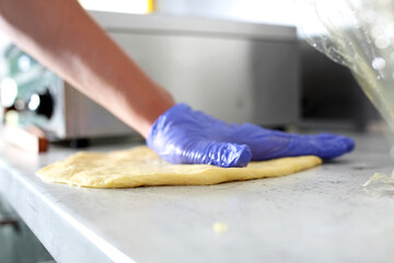 Making Hungarian langos in a protective gloves, in a food truck, restaurant. Hungarian fast-food, a deep fried flatbread