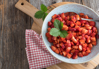 Chopped strawberries in a bowl on wooden table