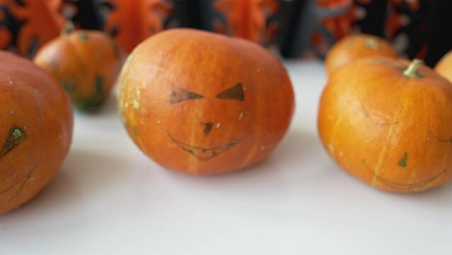 Painted scary happy and fun halloween pumpkins with different facial expression, video for holiday close up. Happy Halloween. Three orange pumpkin for cutting with various festive decor on background