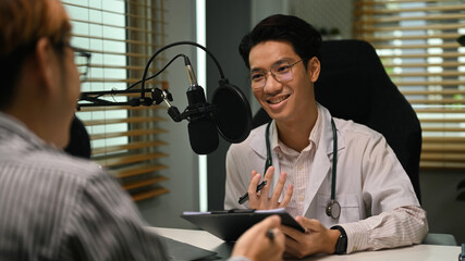 Friendly doctor in white coat and stethoscope making medication advise via online podcast, online...