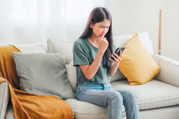 Worried young woman looking at smartphone screen, dissatisfied with bad news message, spam or scam...
