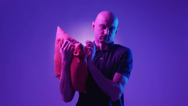 Sweet dreams. Tired man. Night comfort. Exhausted yawning guy putting head on comfortable pillow in hands falling asleep on violet blue neon light background.