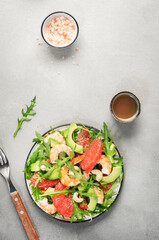 Healthy fresh salad with shrimps, avocado, grapefruit, arugula and cashews. Gray stone kitchen  table background, top view, copy space