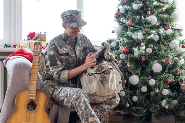 man in military uniform playing acoustic guitar at home at christmas