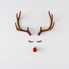 Creative layout made of reindeer antlers, eyelashes and Christmas decoration on white background....