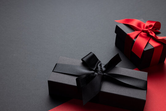 Composition of presents with pink and black ribbons on gray and pink background