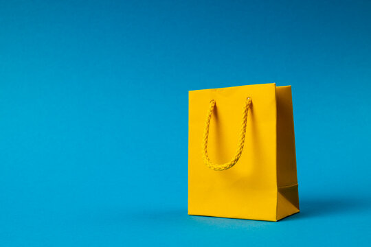 Composition of yellow paper shopping bag on blue background