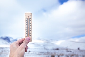 a man holds in his hand a snow thermometer showing the temperature.