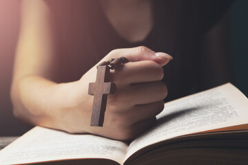 woman praying on book holding cross