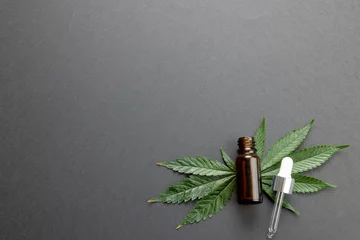 Foto op Canvas Image of marihuana leaf and bottle of cbd oil on grey surface © vectorfusionart