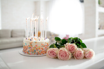 The cake and bouqutte of f;owers lies on the wahite table ay home