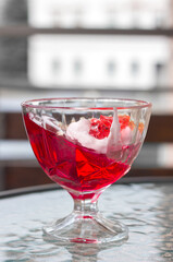 Jelly dessert and whipped cream in a glass glass on a bright light background, tasty and healthy sweets, selective focus