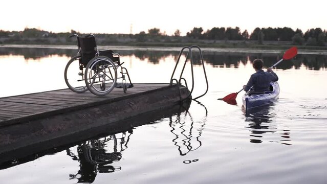 A man with a disability is kayaking against the backdrop of a golden sunset. Unity with the harmony of nature
