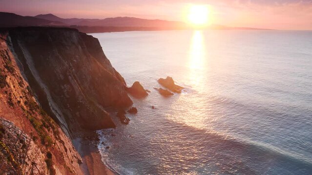 Sunset over rocky cliffs at Asturias coast in north Spain. View from Faro de Cabo Busto. Tourist attraction, place to visit.