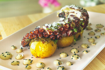 Tasty Grilled Galician octopus leg with roasted potatoes and garlic aioli on wooden table