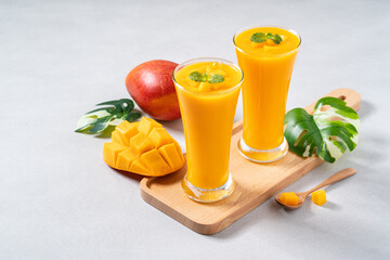 Fresh beautiful delicious mango juice smoothie in glass cup on gray table background.