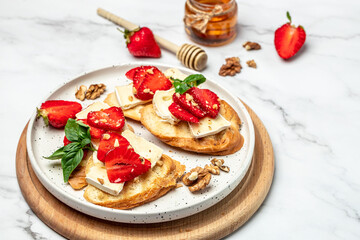 Bruschetta with strawberries, cheese camembert nuts and honey on a light background. banner, menu, recipe place for text, top view