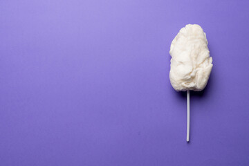 Horizontal image of homemade white candy floss on stick, on purple background with copy space